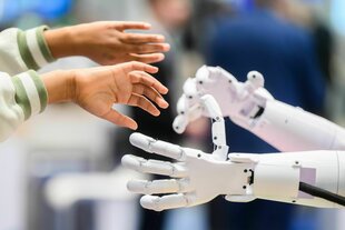 Kinderhände greifen nach Händen eines Roboters