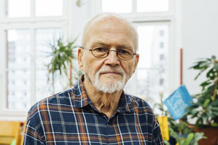 Ein Mann mit Brille und weißem Bart blickt in die Kamera.