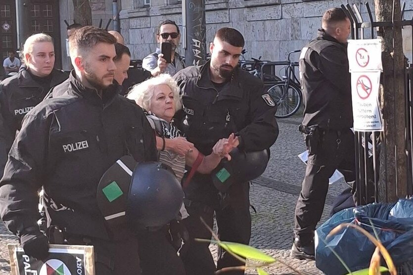 Eine Frau wird von mehreren Polizisten abgeführt